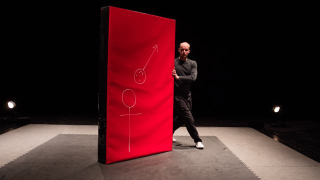 Un porteur apparaît derrière le tapis rouge où deux personnages sont dessinés.
