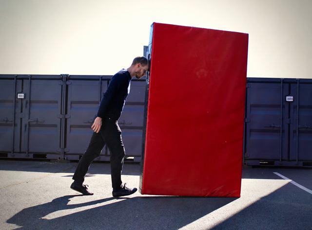 En extérieur : le porteur pose son front contre le tapis rouge.