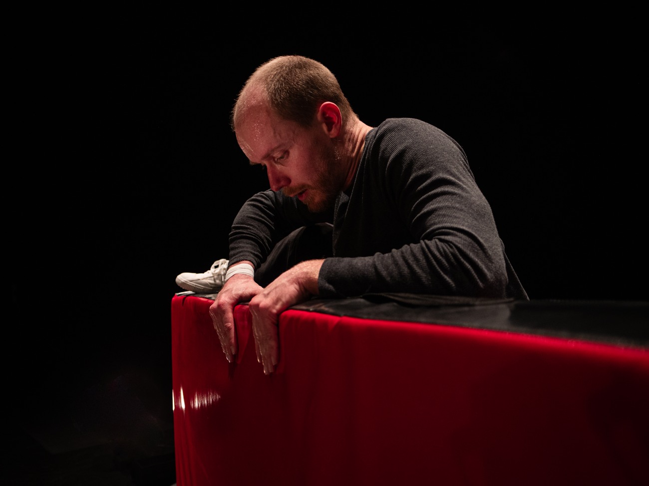 En salle, Jonathan est penché sur le tapis rouge, les mains posées sur son bord.
